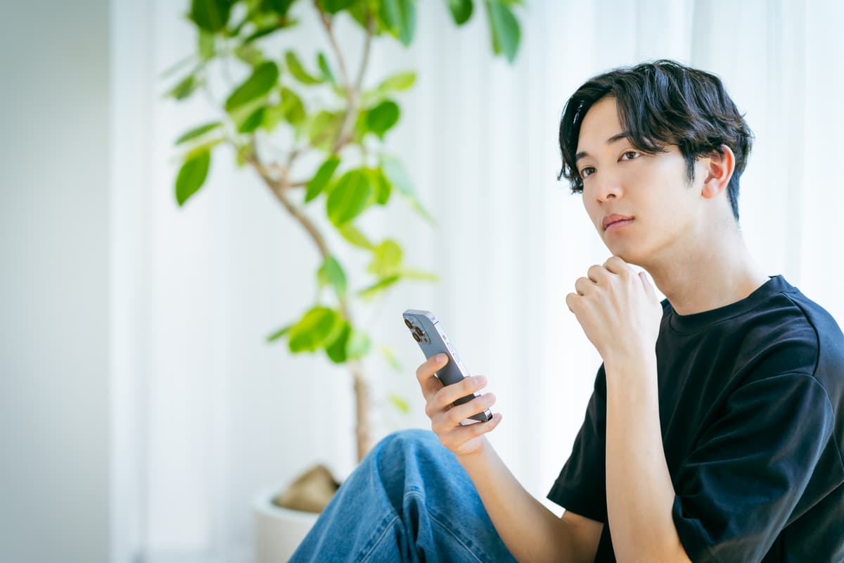 スマホを持って考え込む男性