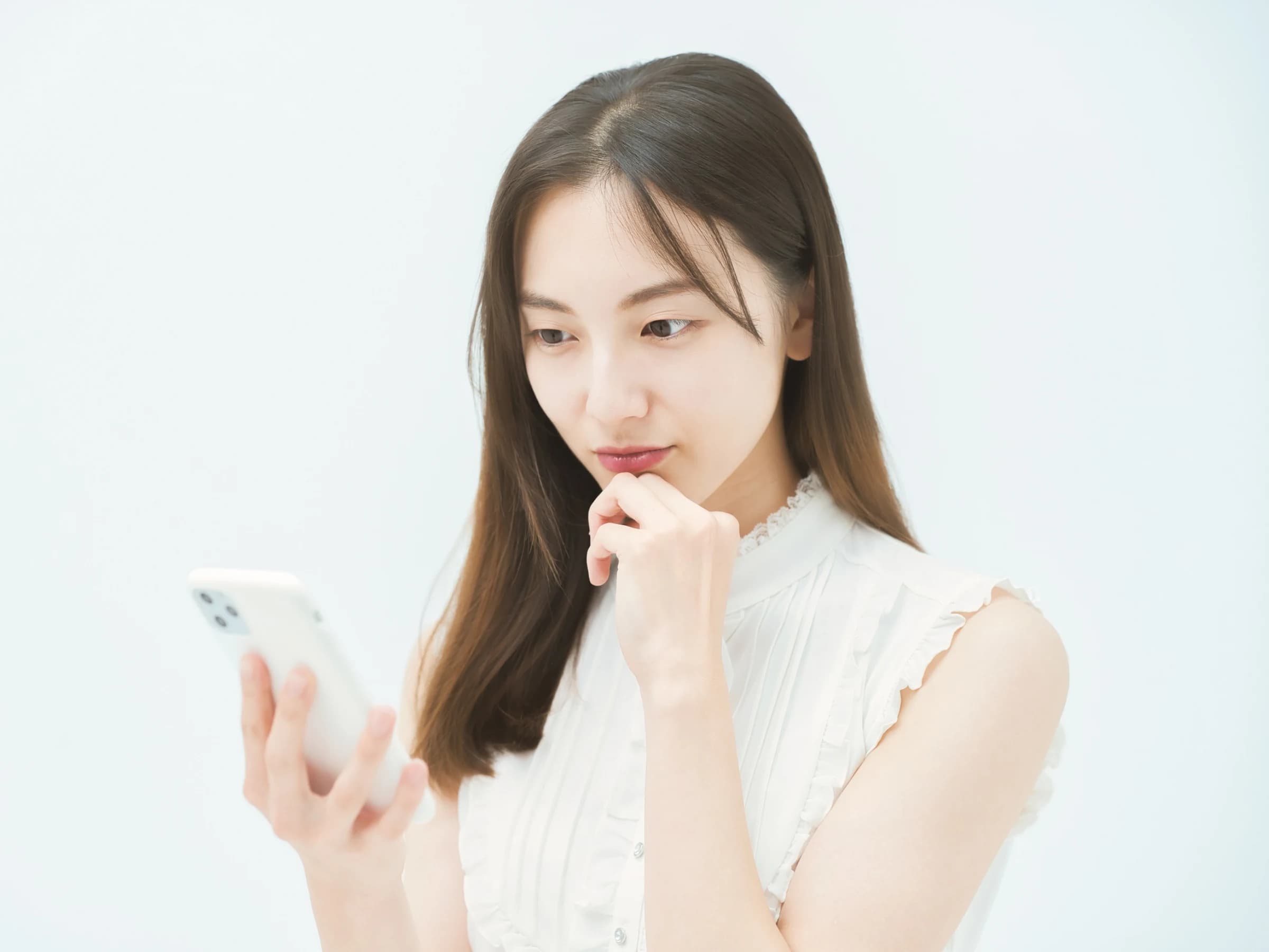 スマートフォンを見ながら自分に合うコーチについて考える日本人女性